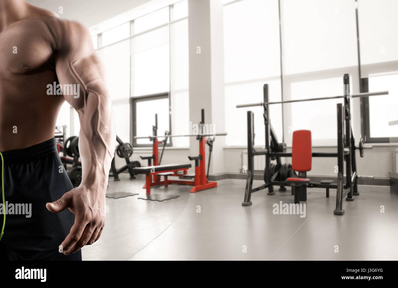 Abstract gym background and strong arm and chest of the bodybuilder Stock Photo