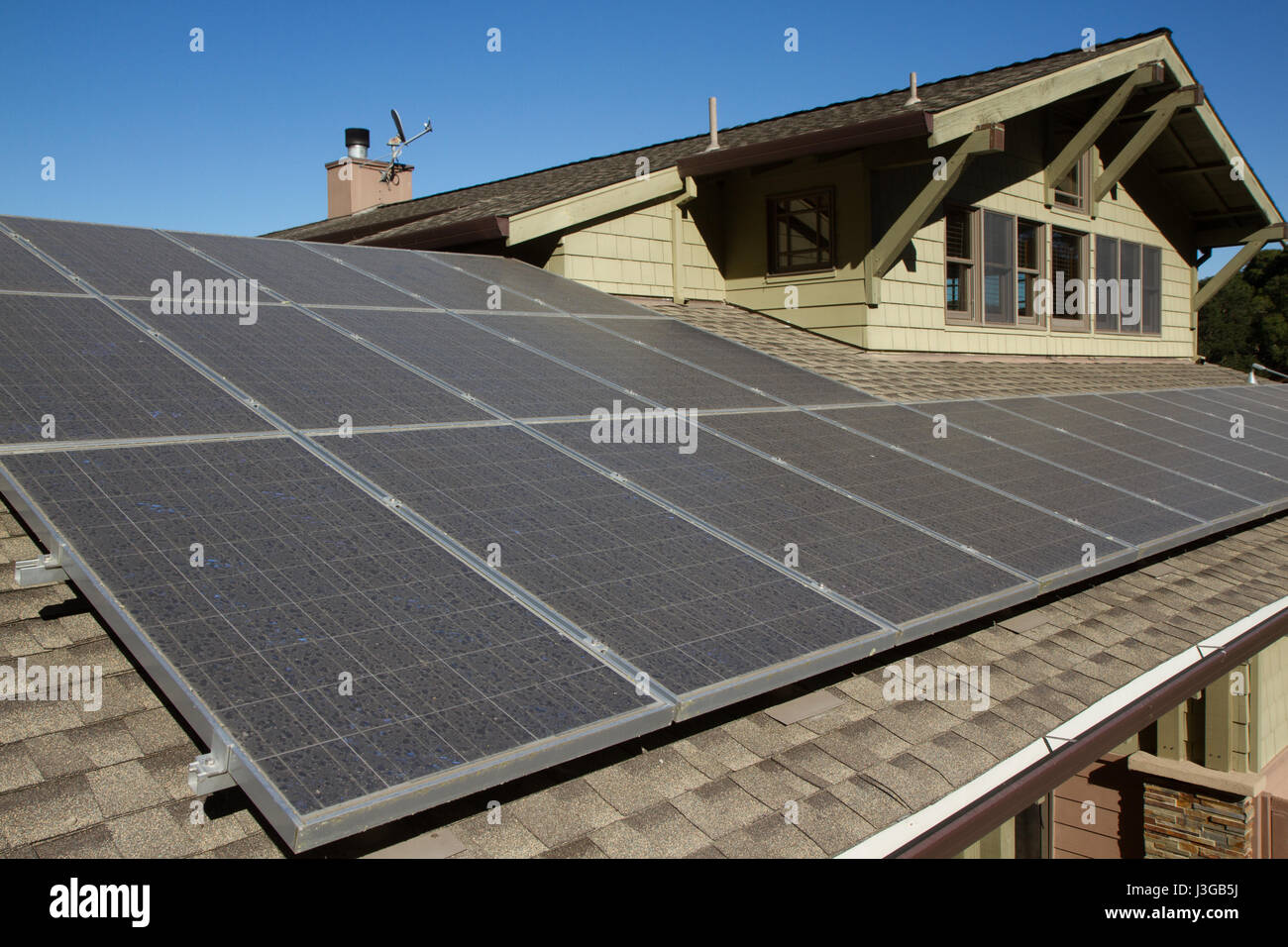 solar panels on roof of house. horizontal orientation, blue sky, gray panels on brown roof. room