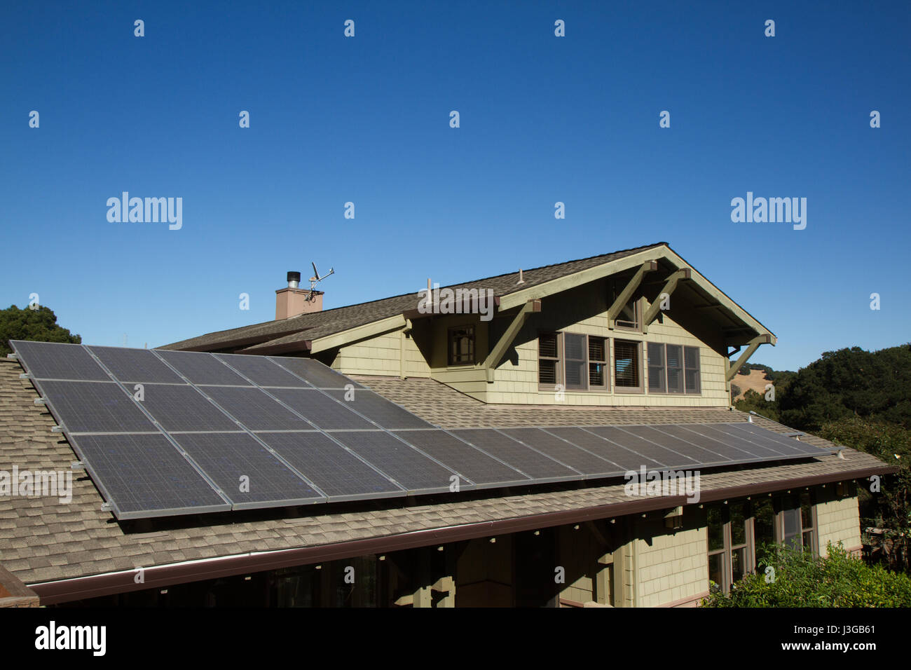 solar panels on roof of house. horizontal orientation, blue sky, gray panels on brown roof. room