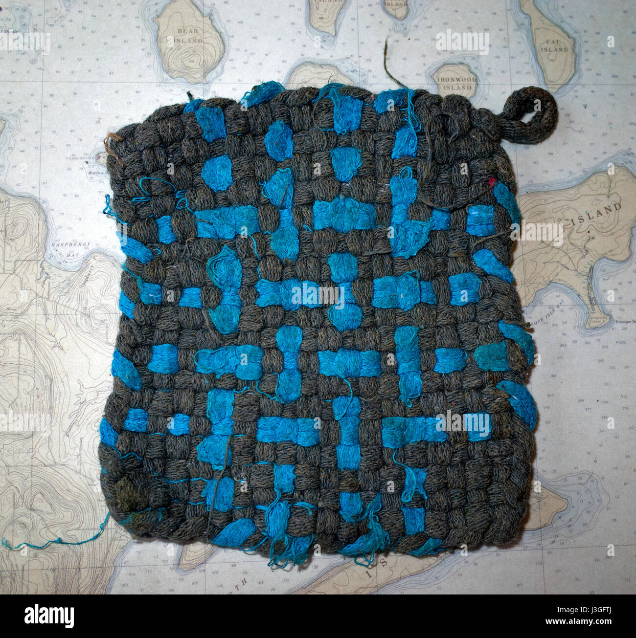 Blue and black hand woven hot pad on a place mat of the Lake Superior Apostle Islands. Cable Wisconsin WI USA Stock Photo