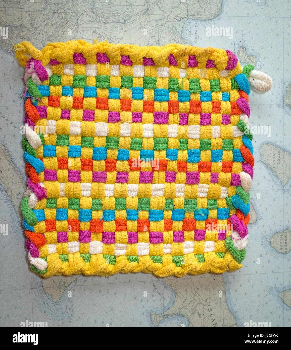Colorful hand woven hot pad on a place mat of the Lake Superior Apostle Islands. Cable Wisconsin WI USA Stock Photo