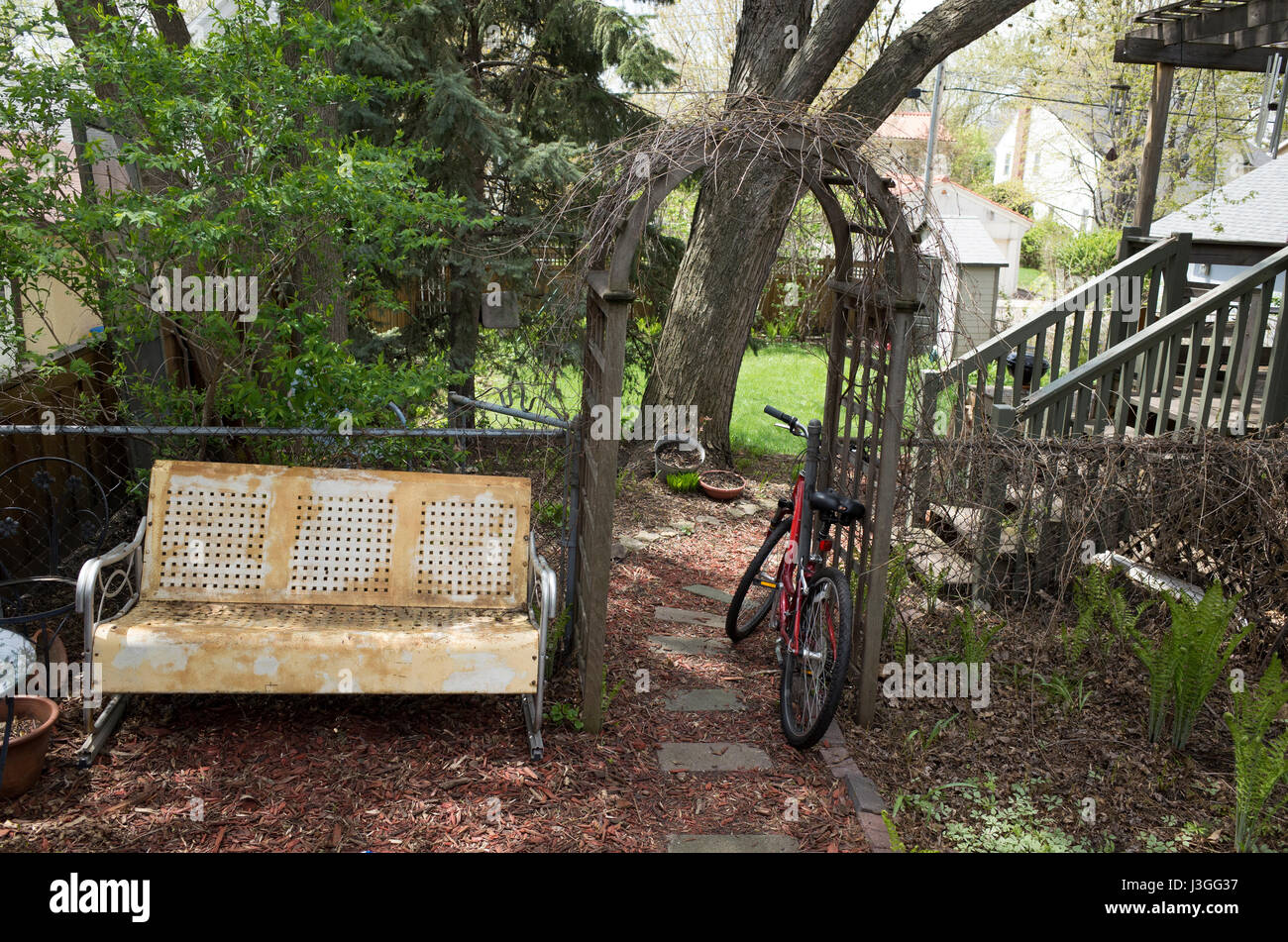 Yellow And White Garden Glider Bench Next To A Curved Arbor