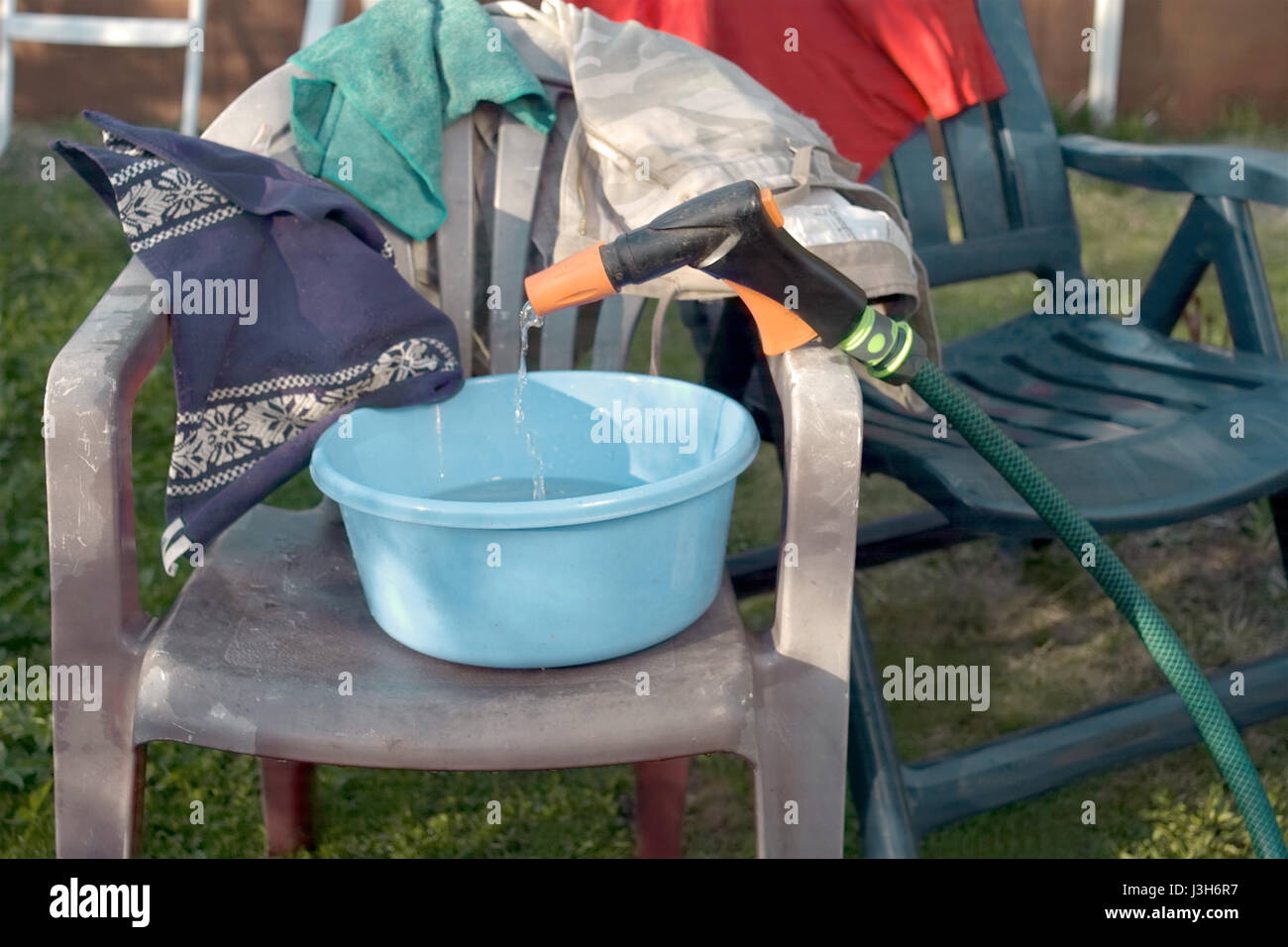 Various laundry and towels hanging on the plastic chairs outdoor Stock Photo