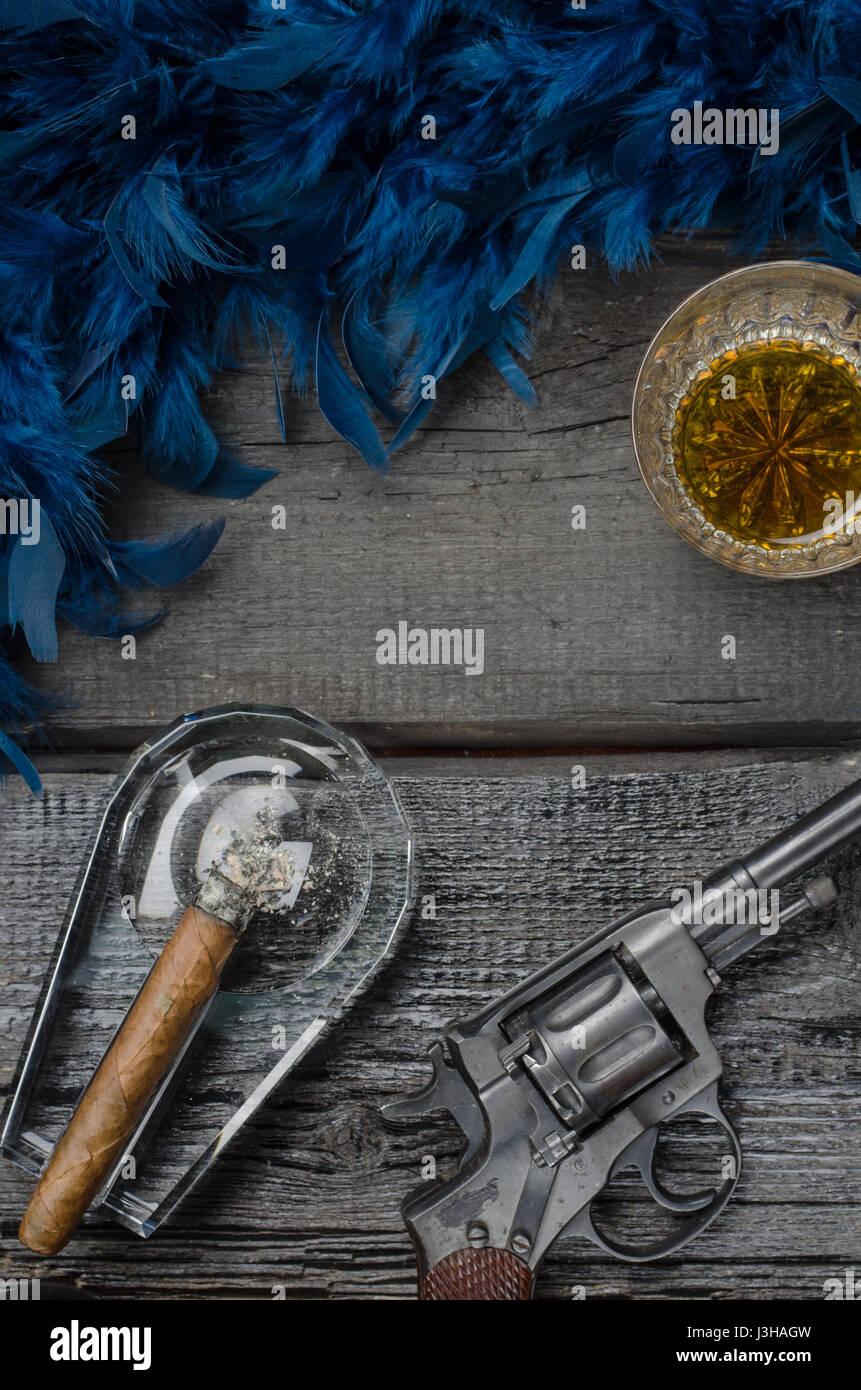 Thompson gun, revolver, cigar on ashtray, whiskey glass and blue feather boa Stock Photo