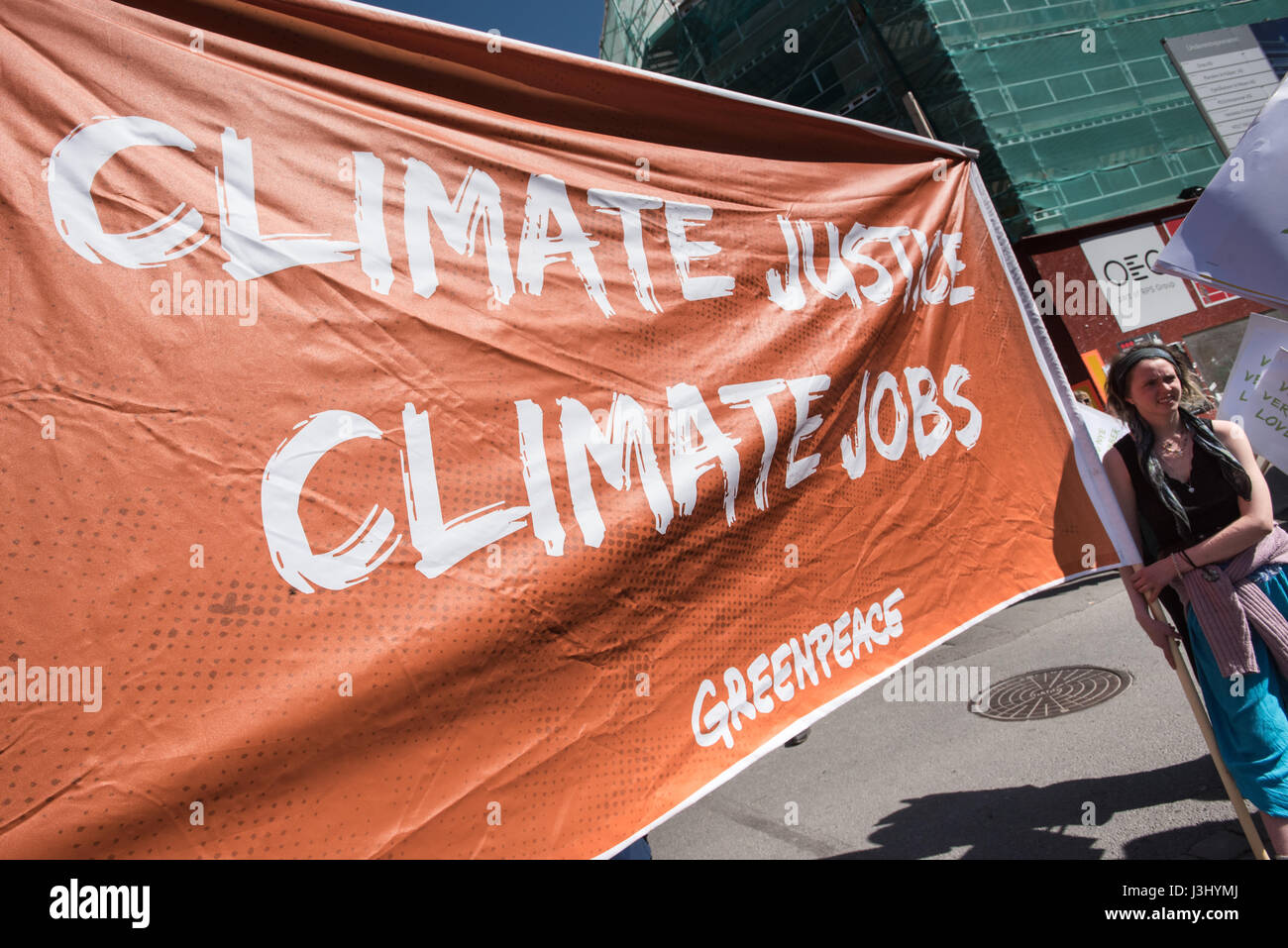 A Greenpeace activist holds a sign reading 'Climate Justice, Climate Jobs' at the annual May Day celebration in Oslo, Norway, May 1, 2017. Stock Photo
