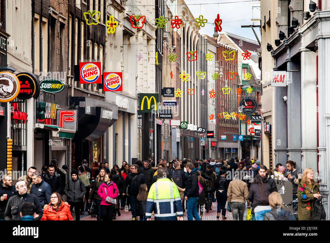 Crowded shopping street with many people and shops signs on famous Nieuwendijk street in Amsterdam, Netherlands Stock Photo