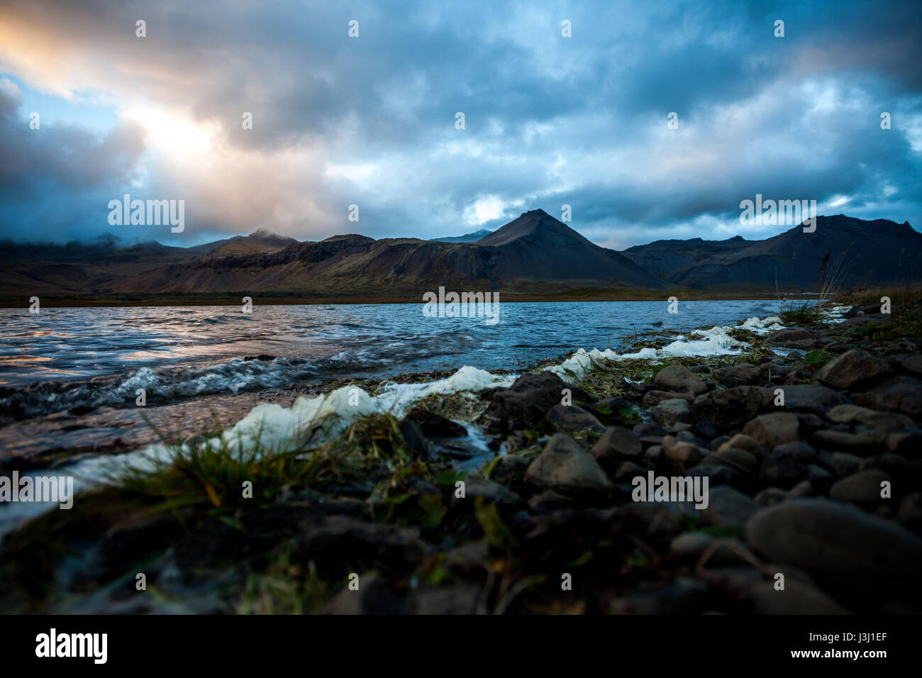 Landscape with lake and mountain range. Light reflections in the water. Tough nature in Iceland at evening. Stock Photo