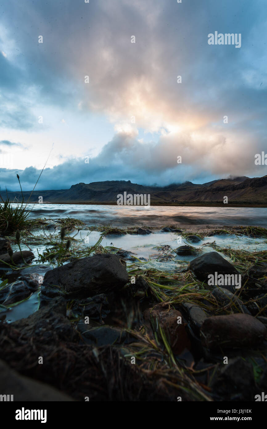 Landscape with lake and mountain range. Light reflections in the water. Tough nature in Iceland at evening. Stock Photo
