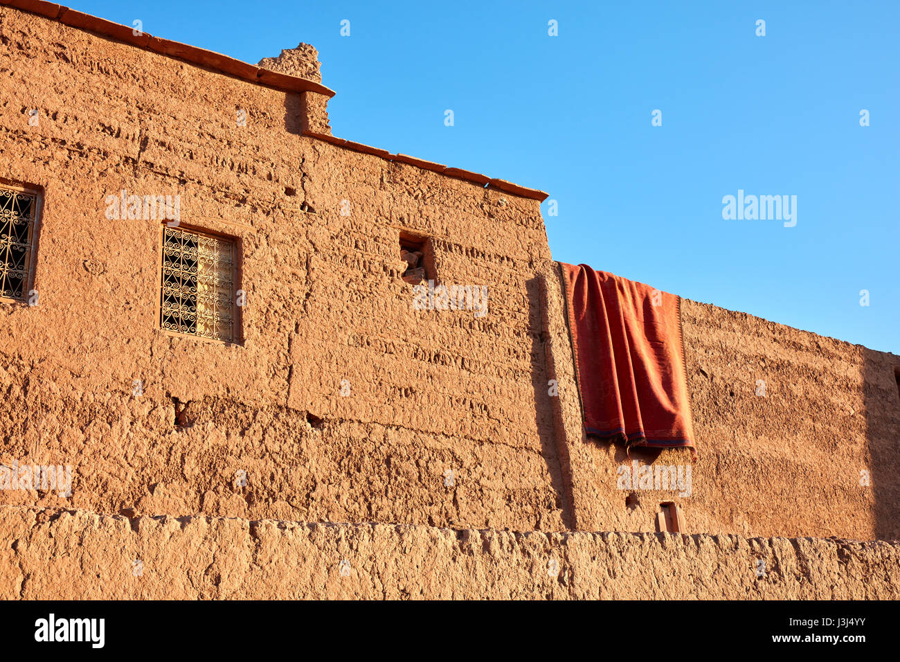 Drying carpet on the earthen walls of the house, Morocco Stock Photo