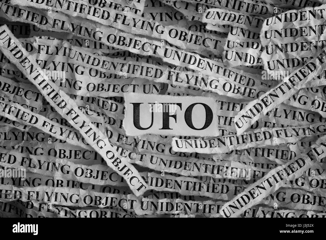 Torn pieces of paper with abbreviation UFO. Unidentified flying object. Concept Image. Closeup. Stock Photo