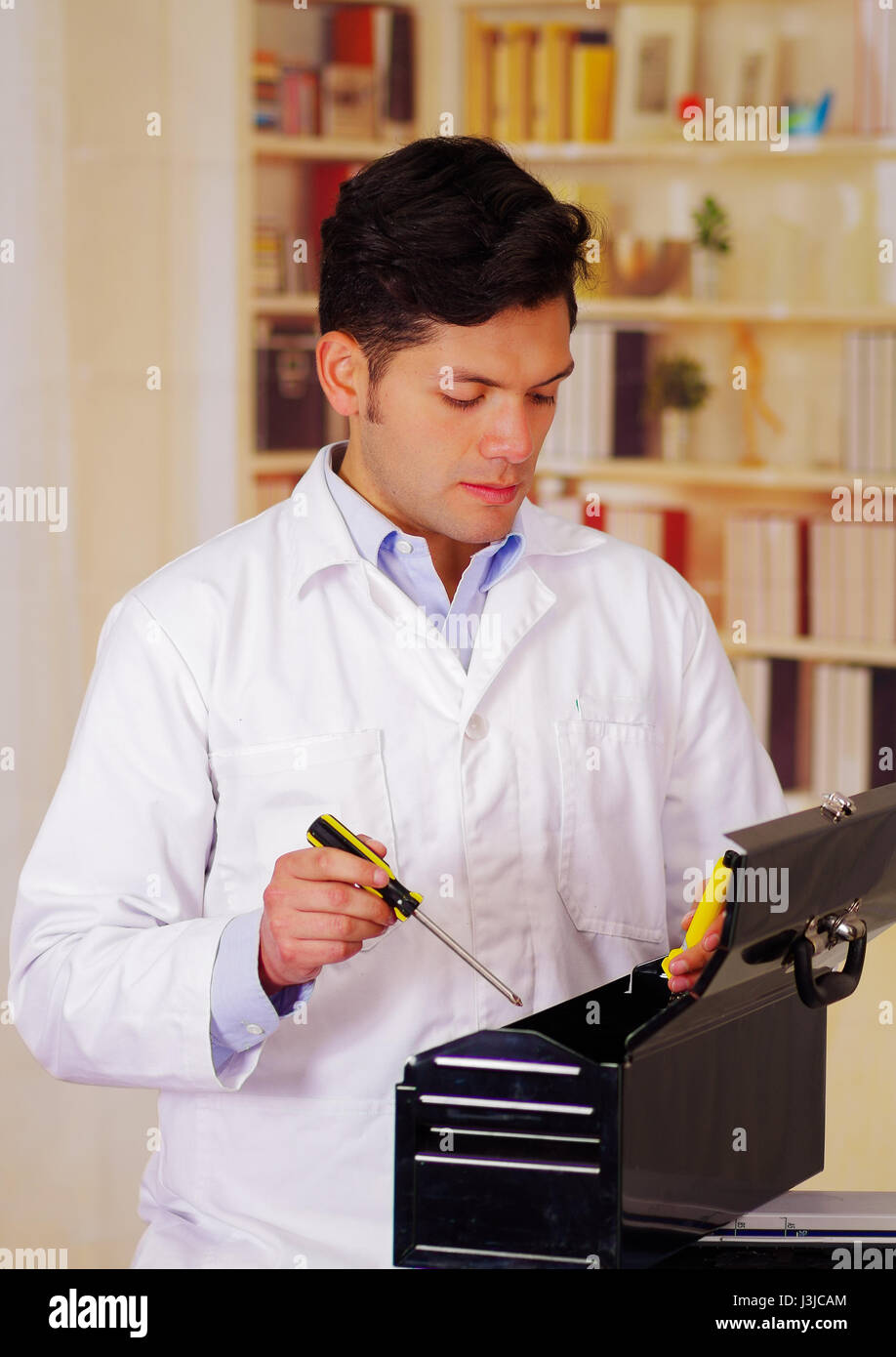 Hardworking Man apen a black tool box and holding a screwdriver in his hand. Stock Photo