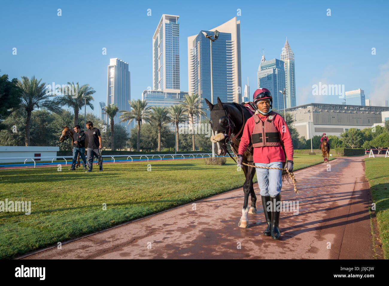 United Arab Emirates Jockey leading horse on track with skyscrapers