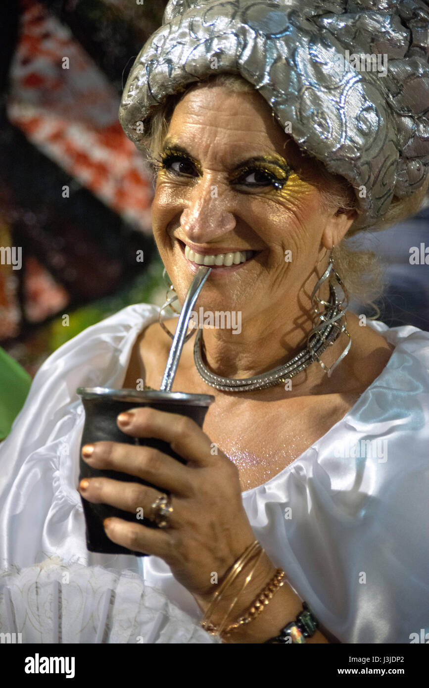 Old woman mama vieja drinking mate. Traditional Murgas and samba schools during the Llamadas (the calling) procession that officially starts the carni Stock Photo