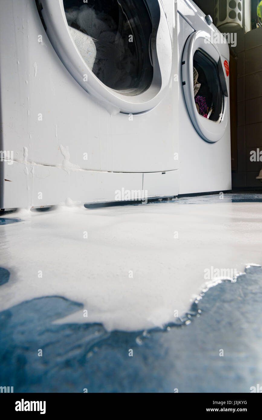Soap bubbles pour out of a leaking washing machine. Stock Photo