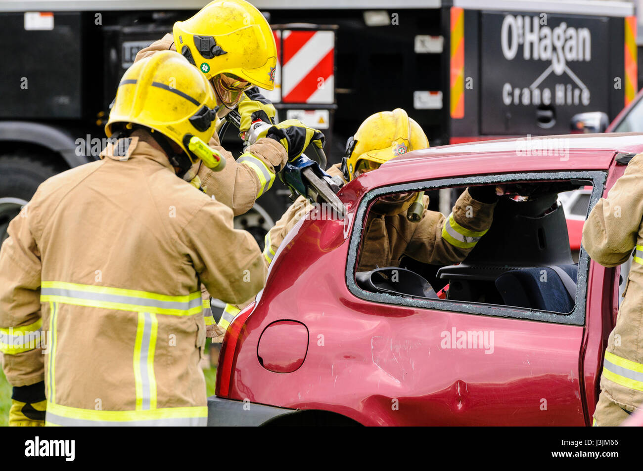 Firecrew from Northern Ireland Fire and Rescue Service demonstrate how to use hydraulic cutting equipment to free a trapped driver from a car after an Stock Photo