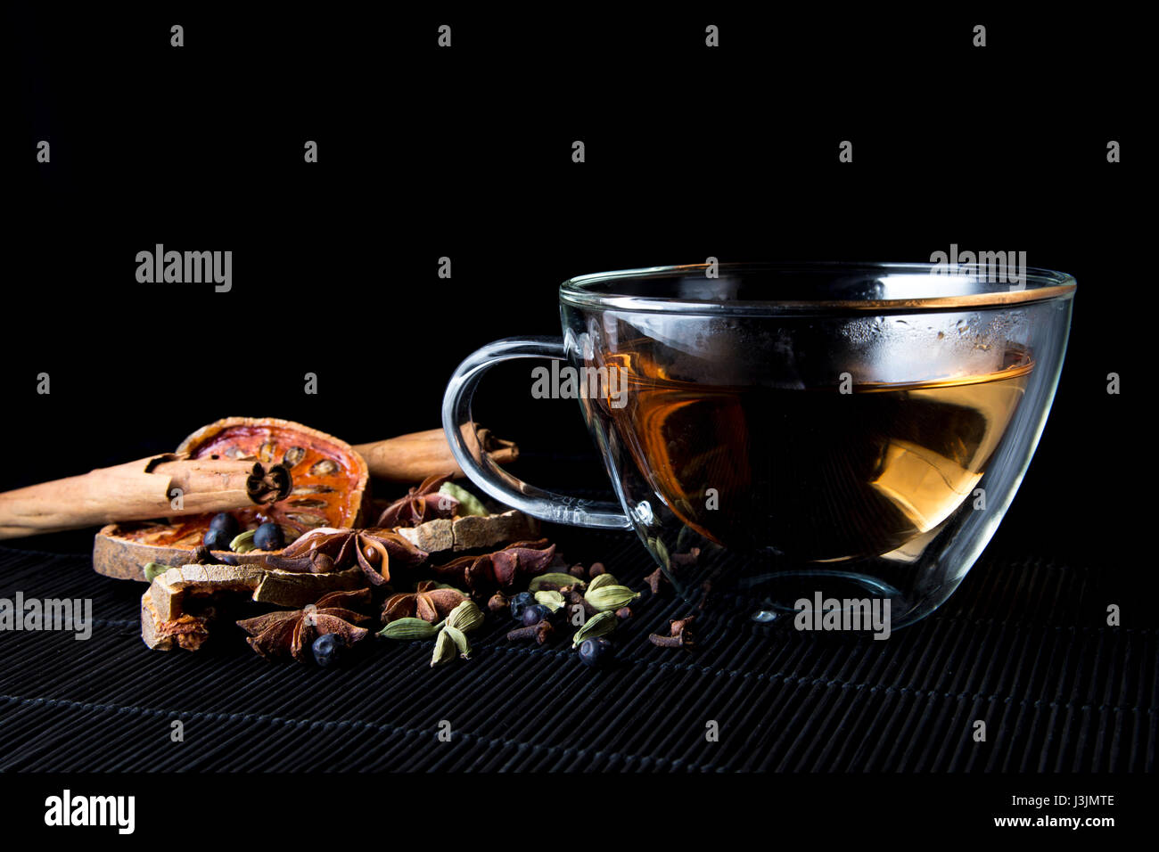 Warming spices and tea infusion on bamboo mat - cinnamon sticks, cardamom, cloves, bael fruit, juniper berries and star anise Stock Photo