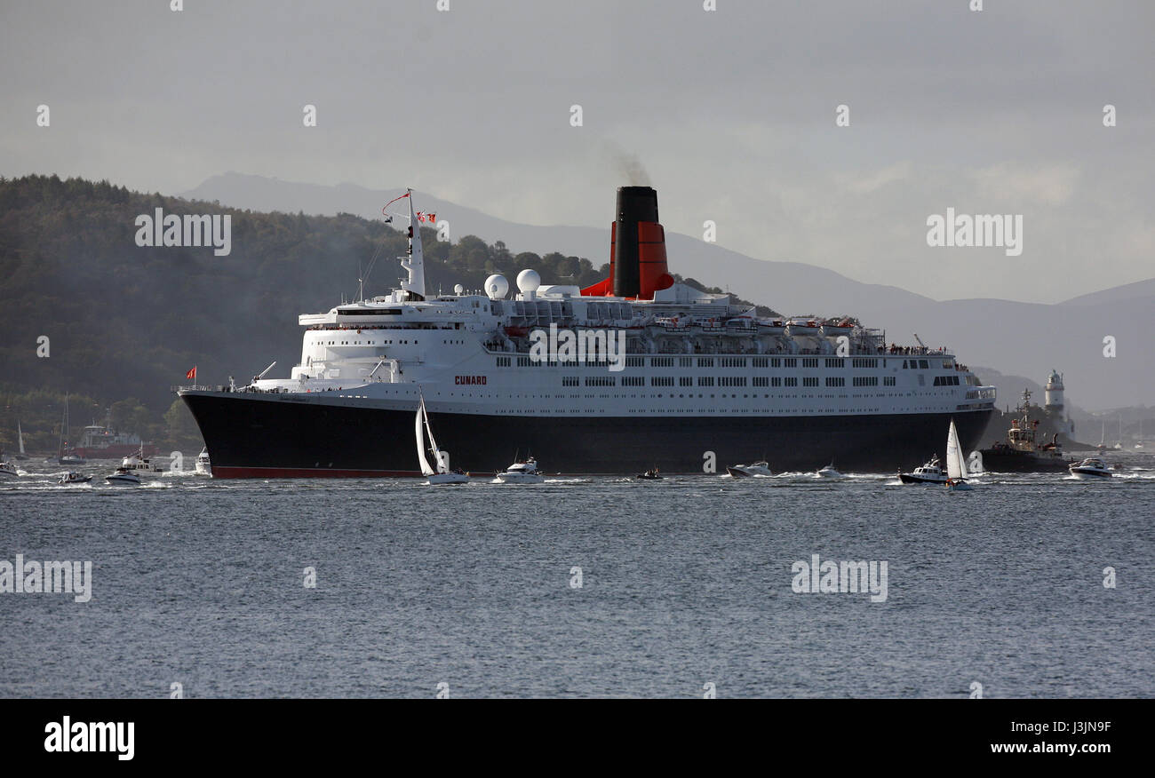 Cunard liner QE2 sailing, up the River Clyde accompanied with a flotilla of small boats on her final trip passing the Cloch Lighthouse Scotland UK Stock Photo