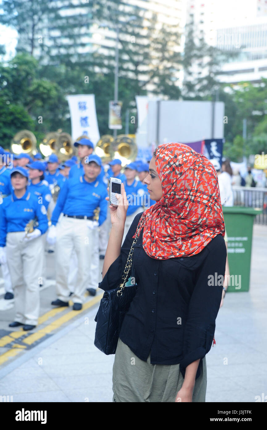 A woman in a hijab takes a picture of the Establishment Day parade on July 1 in Hong Kong, China. Stock Photo