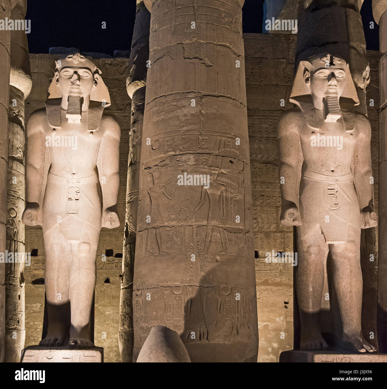 Pair of statues showing Ramses II in Luxor Temple lit up during night ...