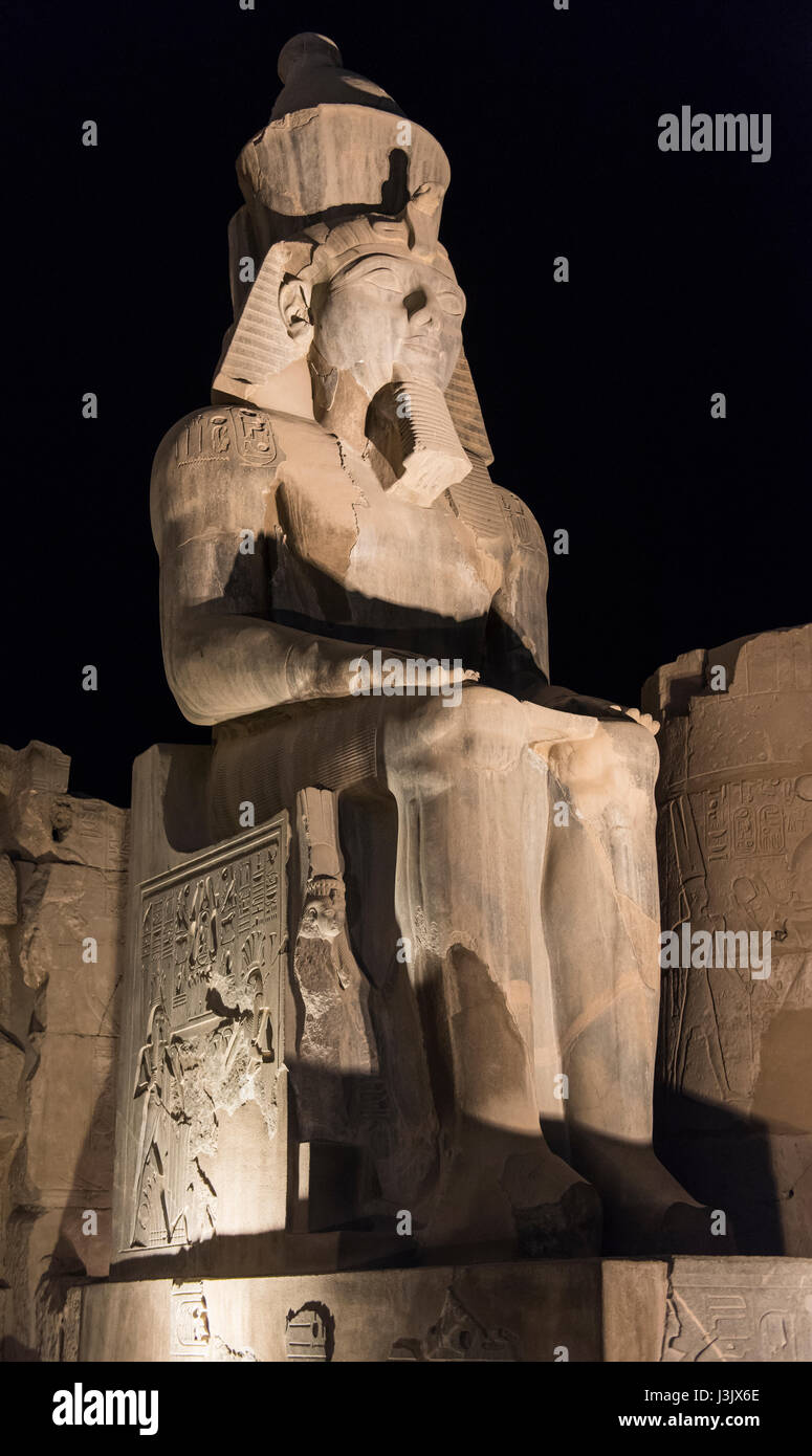 Ancient sitting statue of Ramses II in Luxor Temple lit up at night Stock Photo