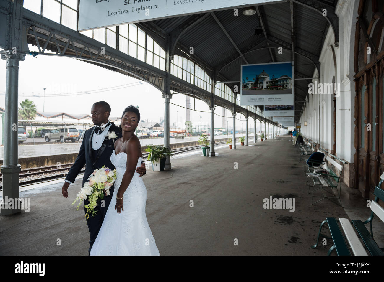 A newly wed couple take shelter from the rain at the historic Caminho de Ferro de Mocambique Maputo railway station in Mozambique Stock Photo