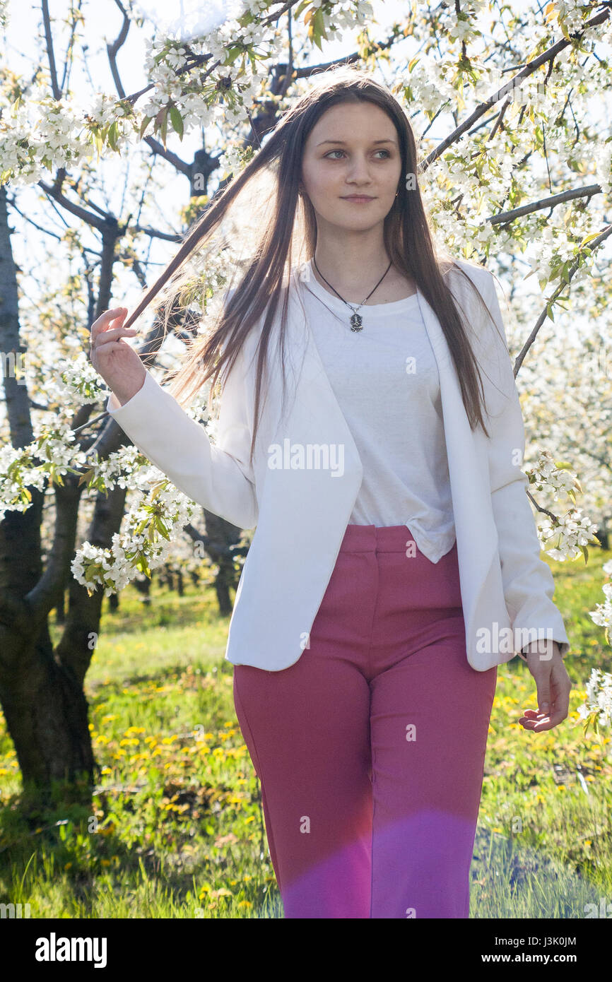 Portrait of a beautiful young girl in a blooming garden against a ...