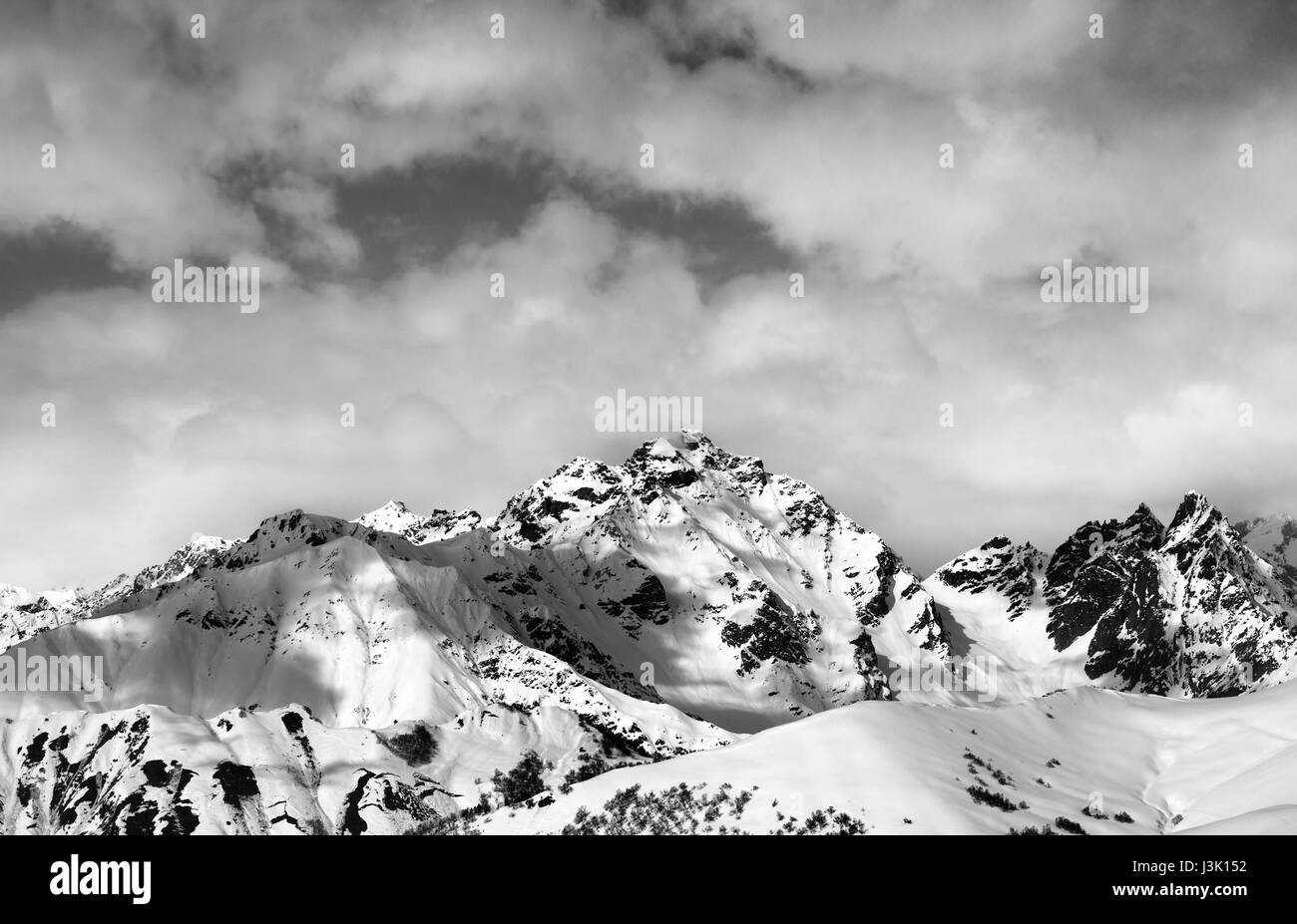 Black and white snow slope and winter sunlight mountains in clouds. Caucasus Mountains, Svaneti region of Georgia. Stock Photo
