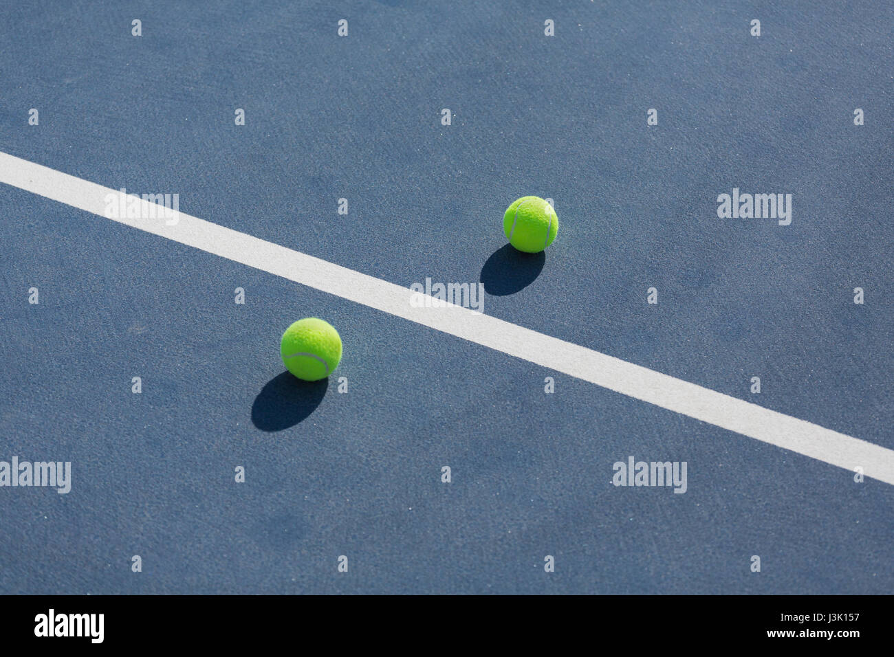 tennis balls on blue hard court divided with white line Stock Photo