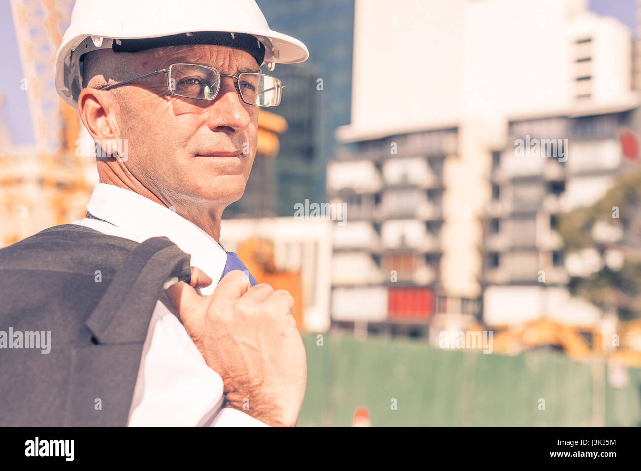 Senior elegant builder man in suit at construction site on sunny Stock ...