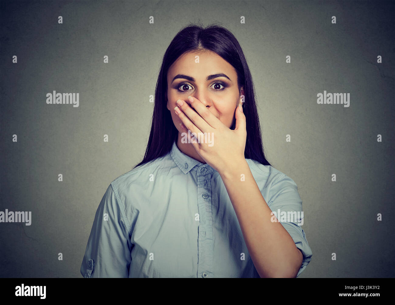 Woman looking surprised in full disbelief hand over wide open mouth isolated gray wall background. Stock Photo