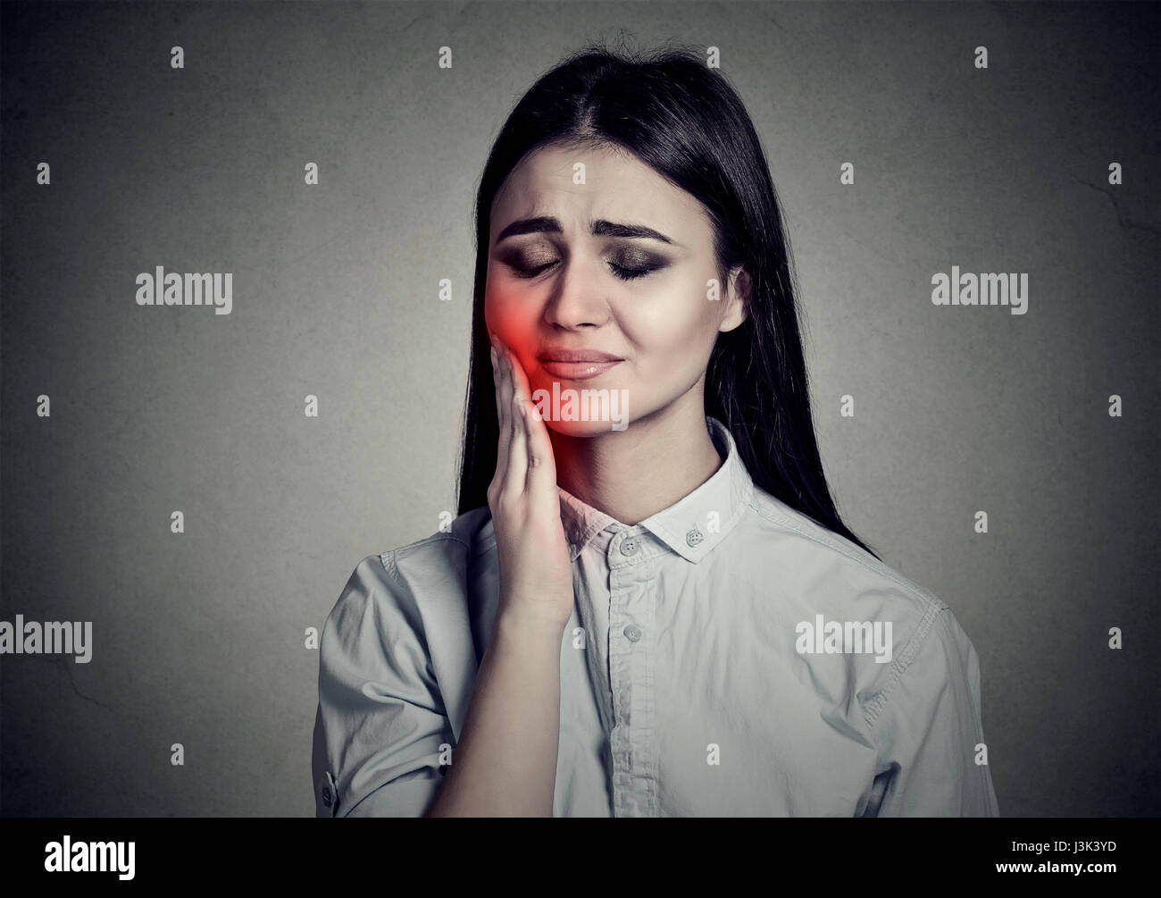 Woman with sensitive toothache crown problem suffering from pain touching outside mouth with hand isolated on gray background. Negative human emotion  Stock Photo