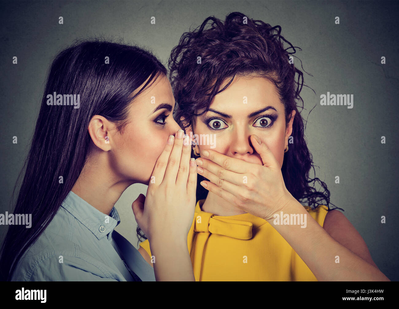 amazed shocked woman listening gossip a secret in the ear Stock Photo