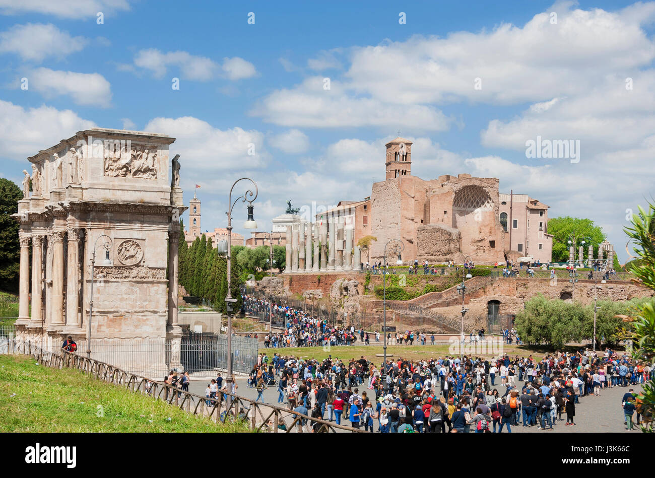 Tourists visit Rome central archaeological area with Arch of  Constantine and ancient Temple of Venus and Roma ruins Stock Photo