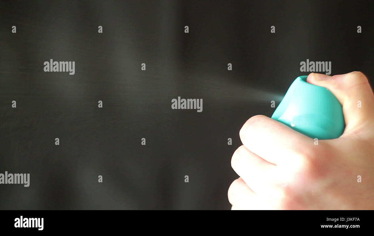 Aerosol can being sprayed against a black background Stock Photo - Alamy