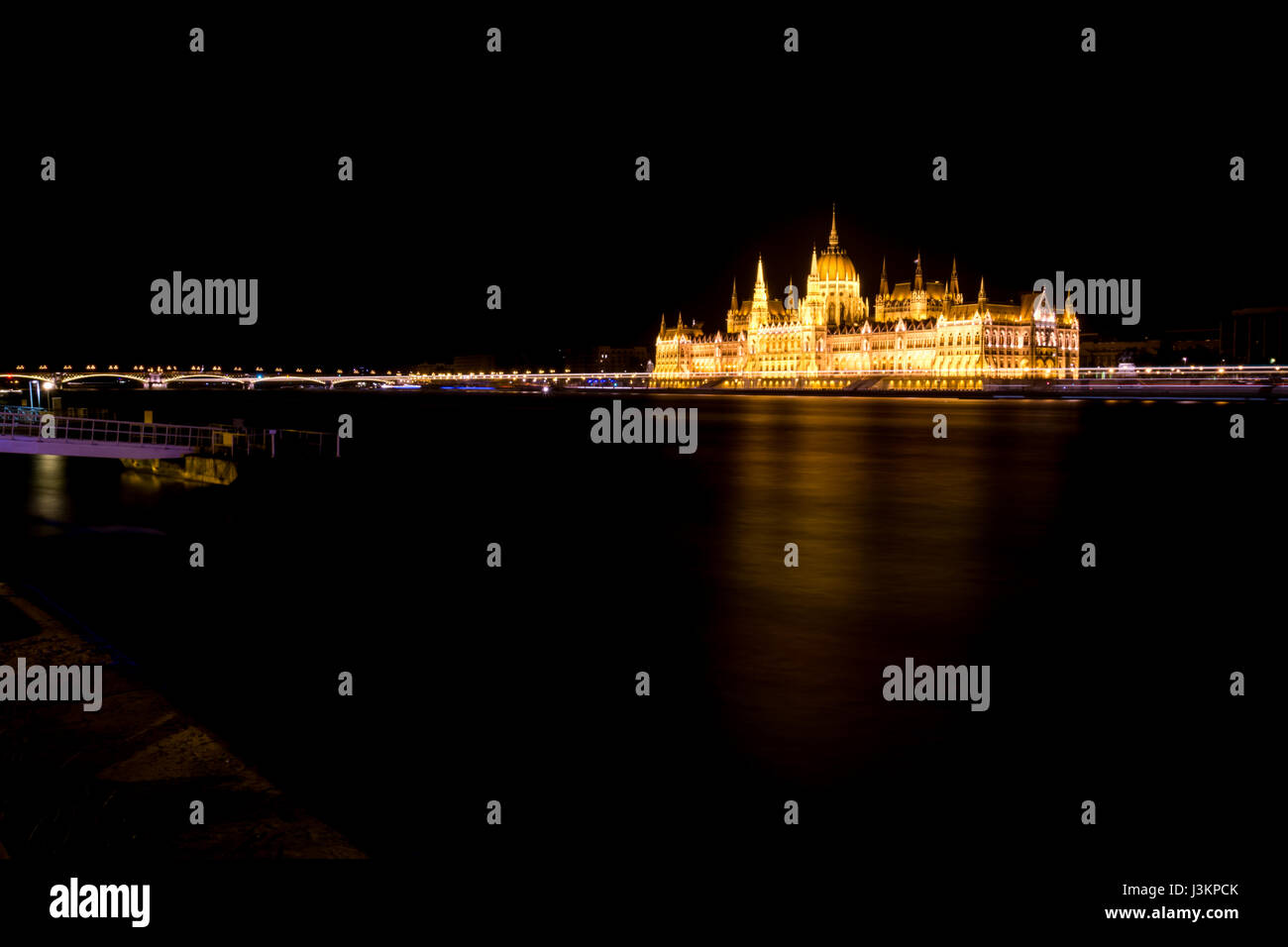 The Hungarian Parliament building lit up at night, across the River Danube, with the lights reflecting in the river. Stock Photo