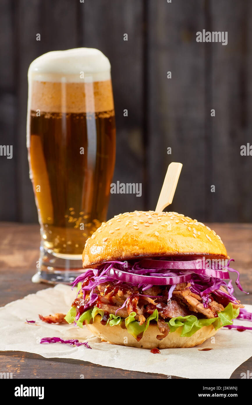 Sandwich with pulled pork and glass of beer on wooden background Stock Photo