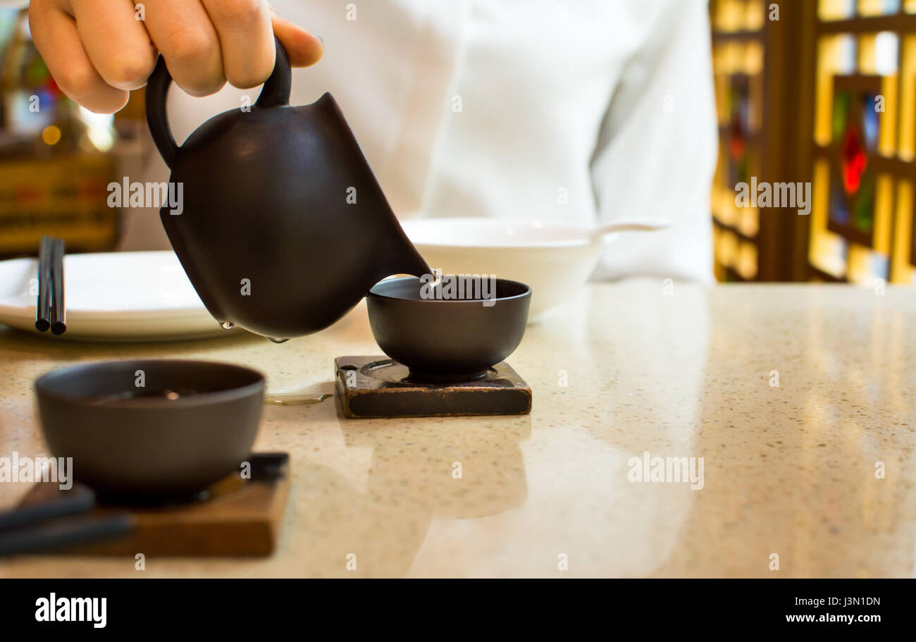 Female pouring tea into ceramic teacup in Chinese restaurant Stock Photo