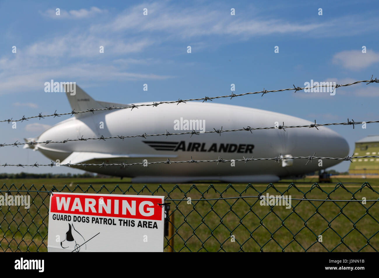 Cardington, Bedfordshire, UK. 7th May, 2017. The Hybrid Air Vehicles Airlander 10 on the new Mobile Mooring Mast at Cardington Airfield. Security sensors on posts inside the fence keep out unwelcome intruders as the aircraft, HAV 304 is almost ready to begin it's 2017 flight test programme. Photo Credit: Mick Flynn/Alamy Live News Stock Photo