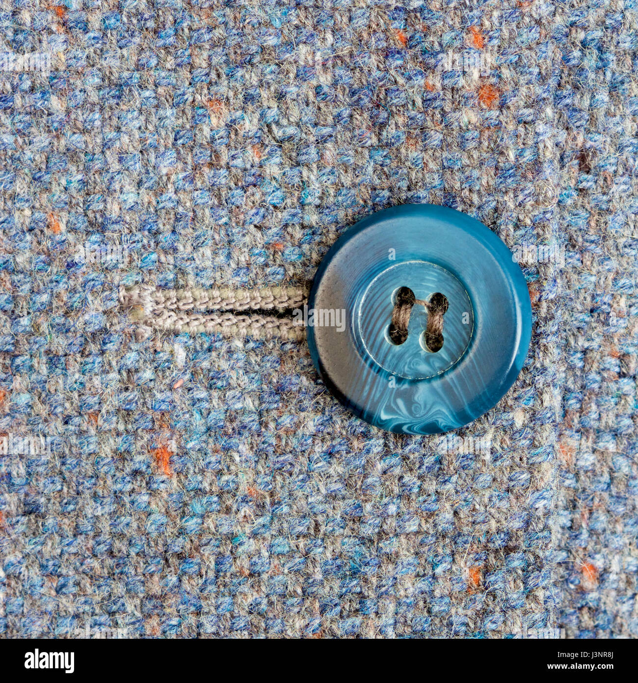 Blue button on a tweed fabric coat. Stock Photo