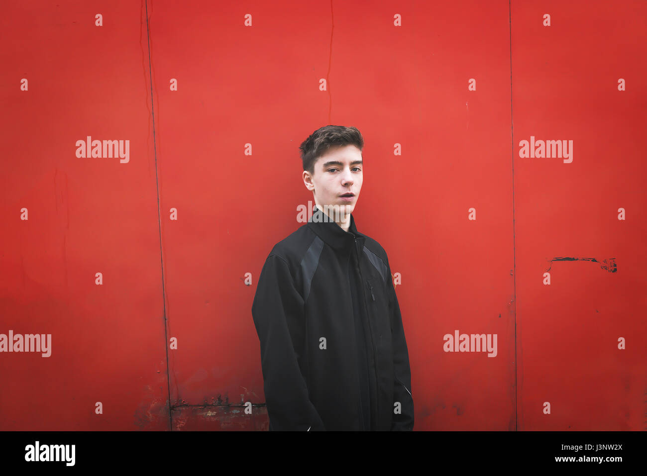 portrait of a young man in front of a red metal wall Stock Photo - Alamy