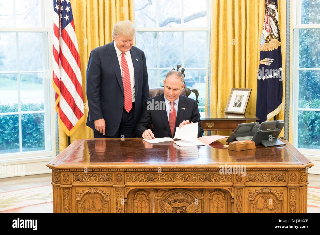 U.S. President Donald Trump looks on as EPA Administrator Scott Pruitt adds his signature to the Waters of the United States Executive Order in the Oval Office of the White House February 28, 2017 in Washington, D.C. The order seeks to roll back a controversial water rule opposed by farmer, rancher and homebuilder groups. Stock Photo