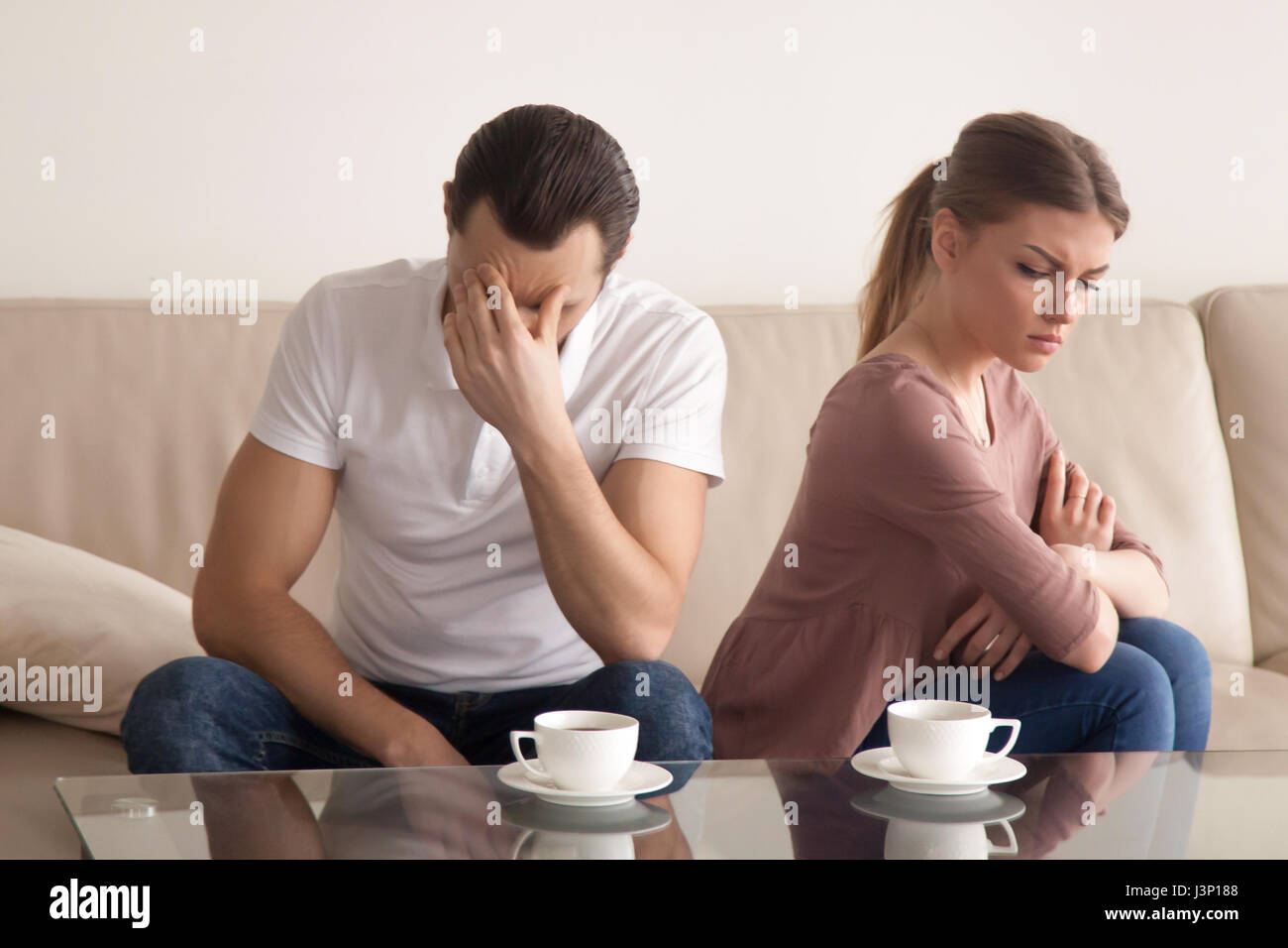 Young couple after arguing, guy tired of quarrelling, woman offe Stock Photo