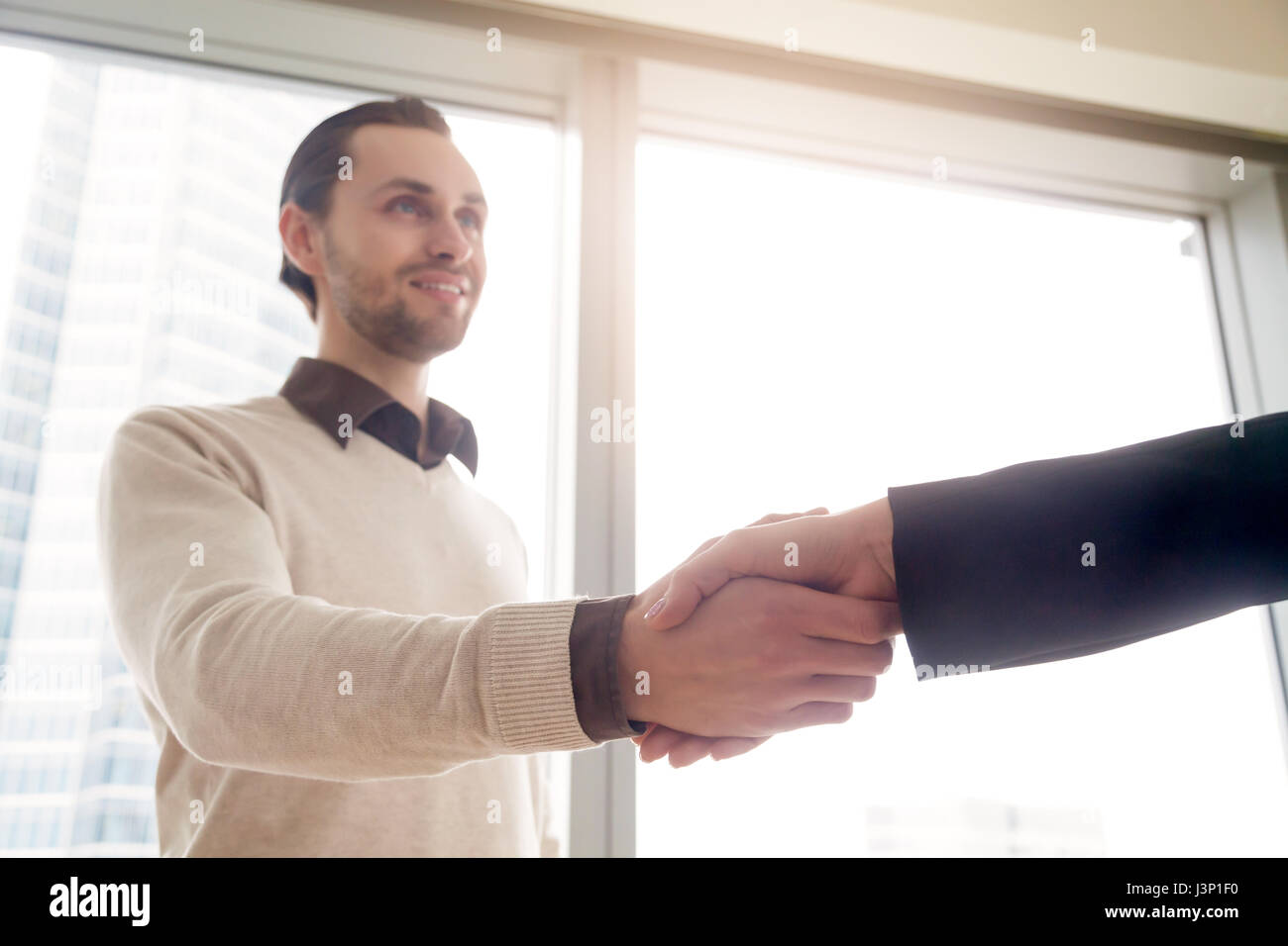 Handsome young businessman shaking female hand, deal or business Stock Photo