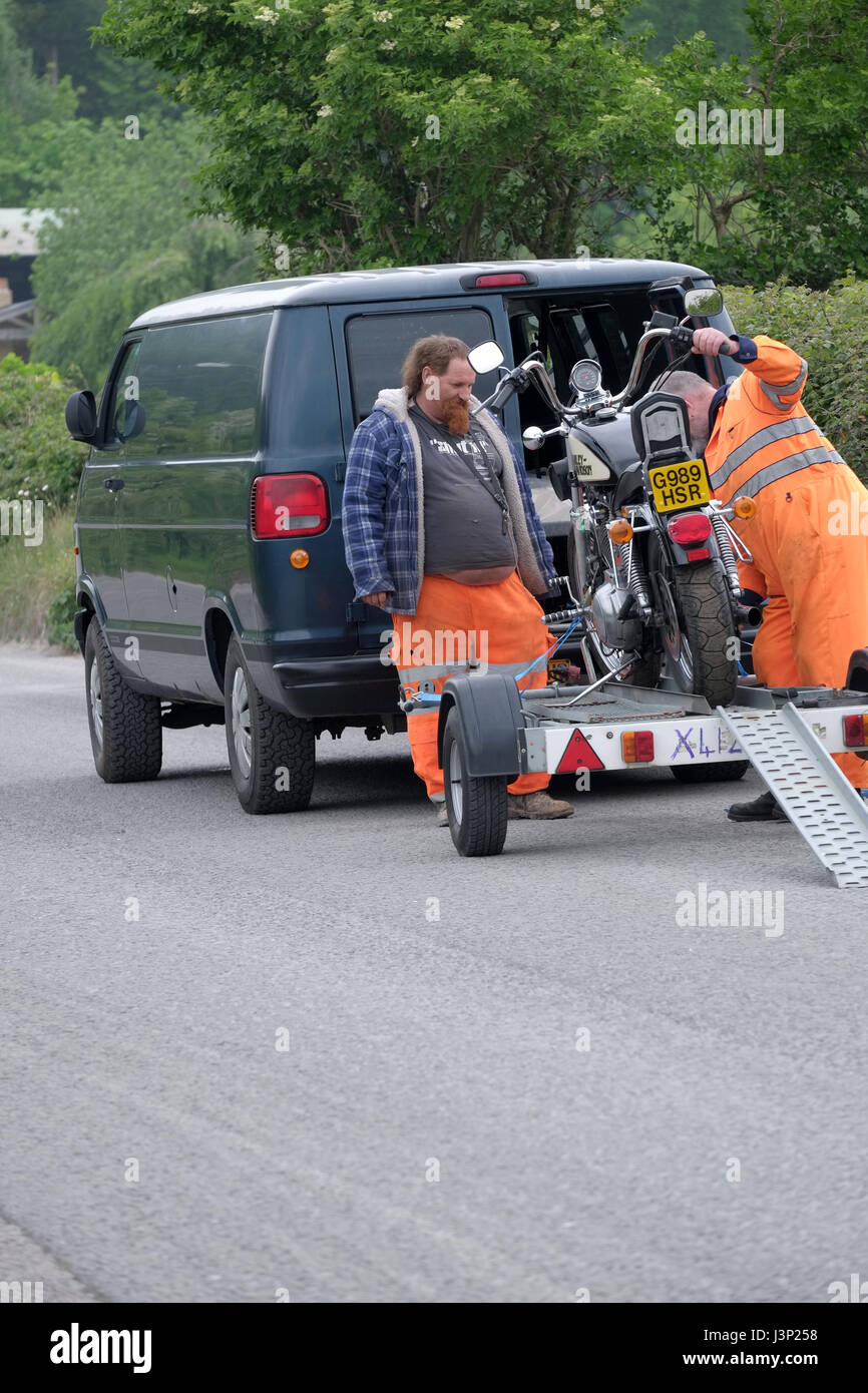 6th May 2017 - two large guys in highway safety gear loading a big Harley Davidson Motor cycle on to a trailer Stock Photo