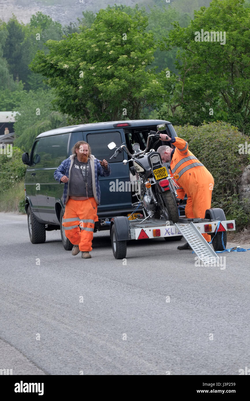 6th May 2017 - two large guys in highway safety gear loading a big Harley Davidson Motor cycle on to a trailer Stock Photo
