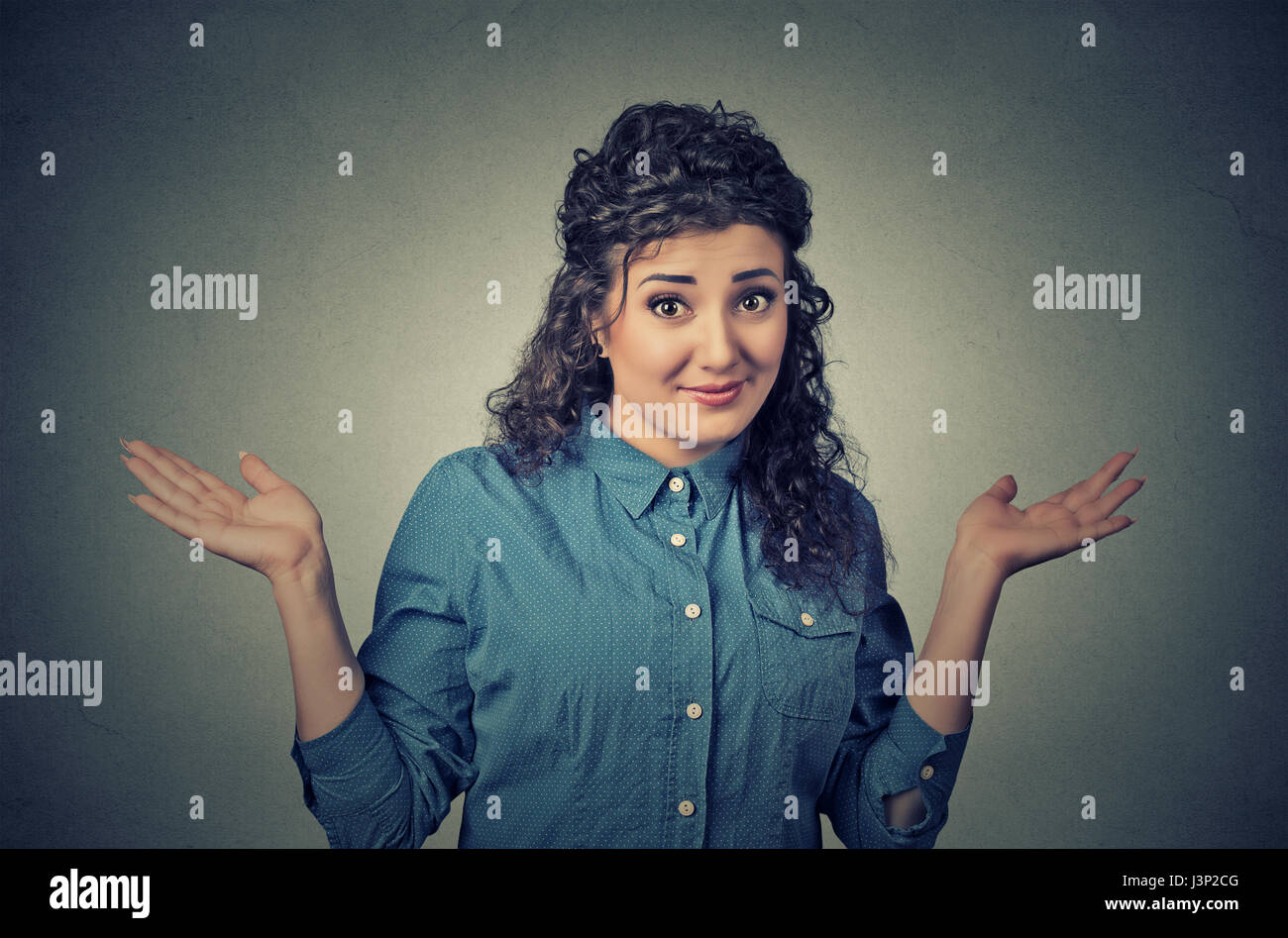 Portrait dumb looking woman arms out shrugs shoulders who cares so what I don't know isolated on gray wall background. Negative human emotion, facial  Stock Photo