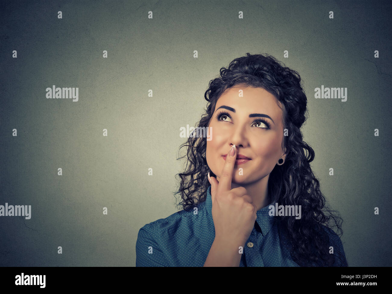 Portrait happy beautiful woman thinking looking up isolated on gray wall background with copy space. Human face expressions, emotions, feelings, body  Stock Photo