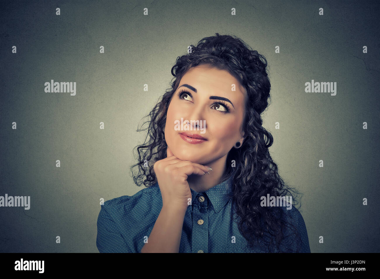 Portrait happy beautiful woman thinking looking up isolated on grey wall background with copy space. Human face expressions, emotions, feelings, body  Stock Photo