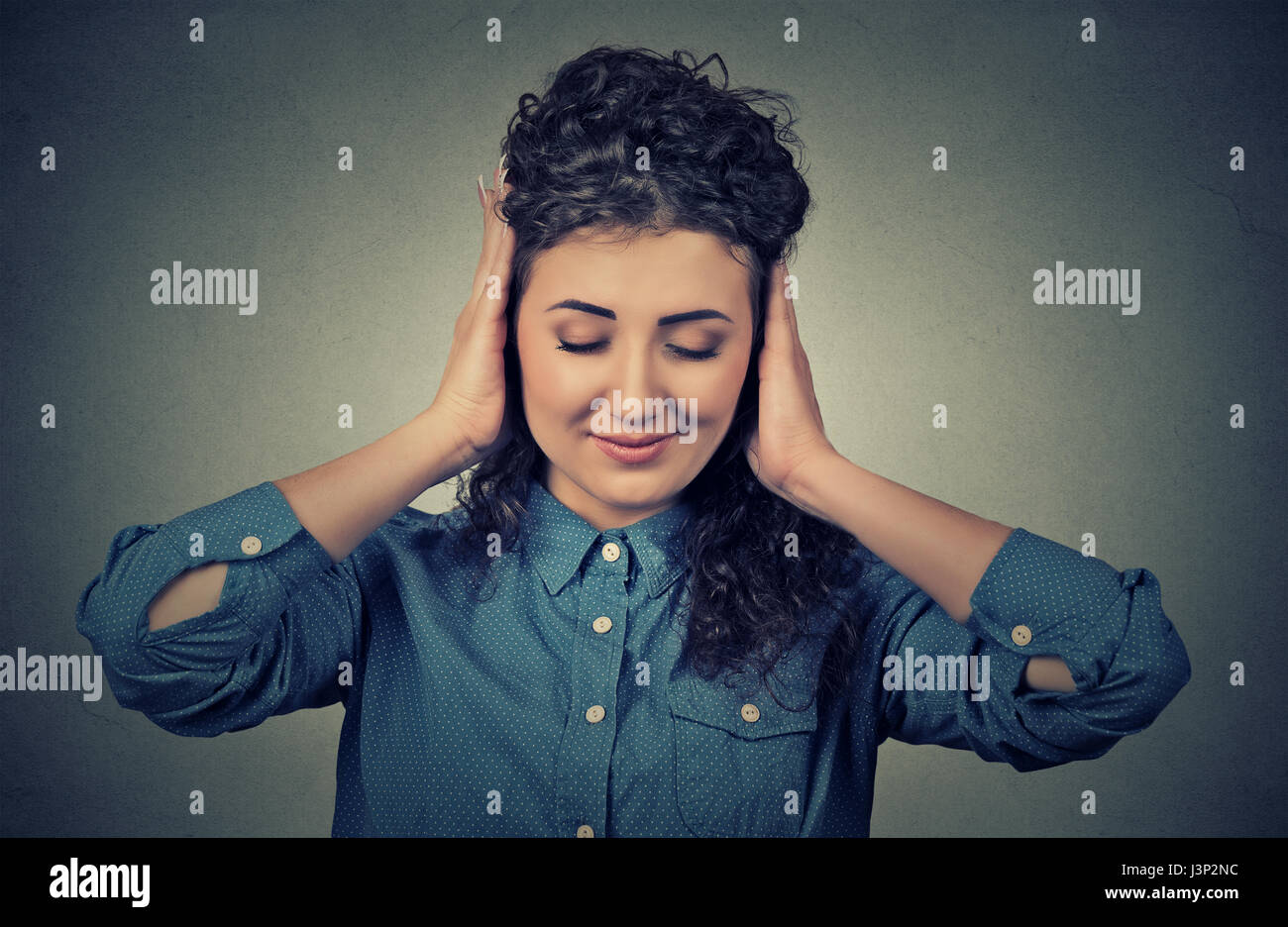 Headshot beautiful young woman covering both ears with her hands isolated on gray wall background Stock Photo
