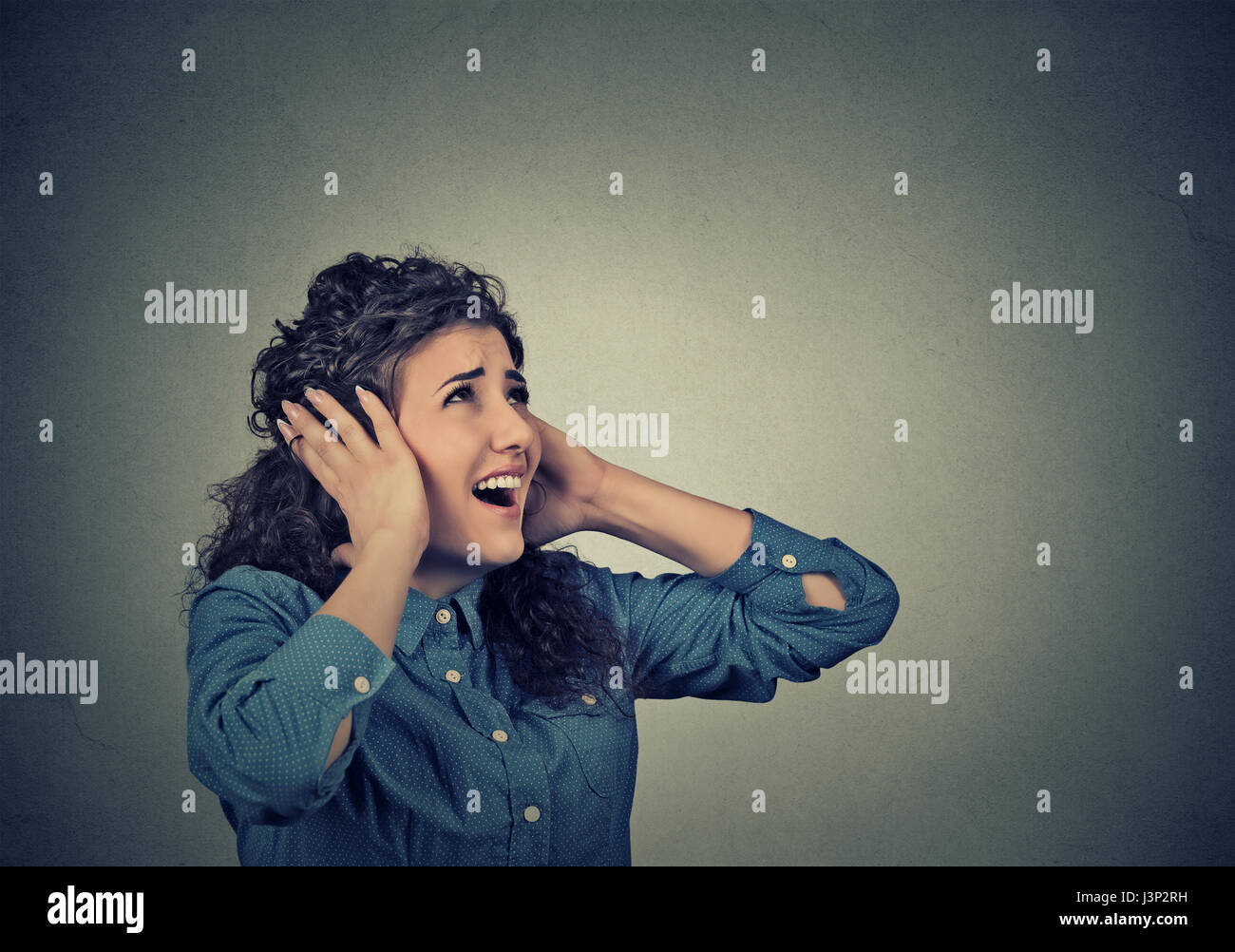 Closeup portrait young unhappy stressed woman covering her ears looking